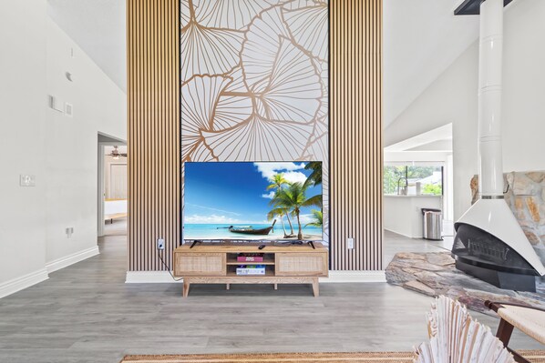 Een moderne woonkamer met een grote flatscreen televisie, houten lambrisering en een stenen open haard.