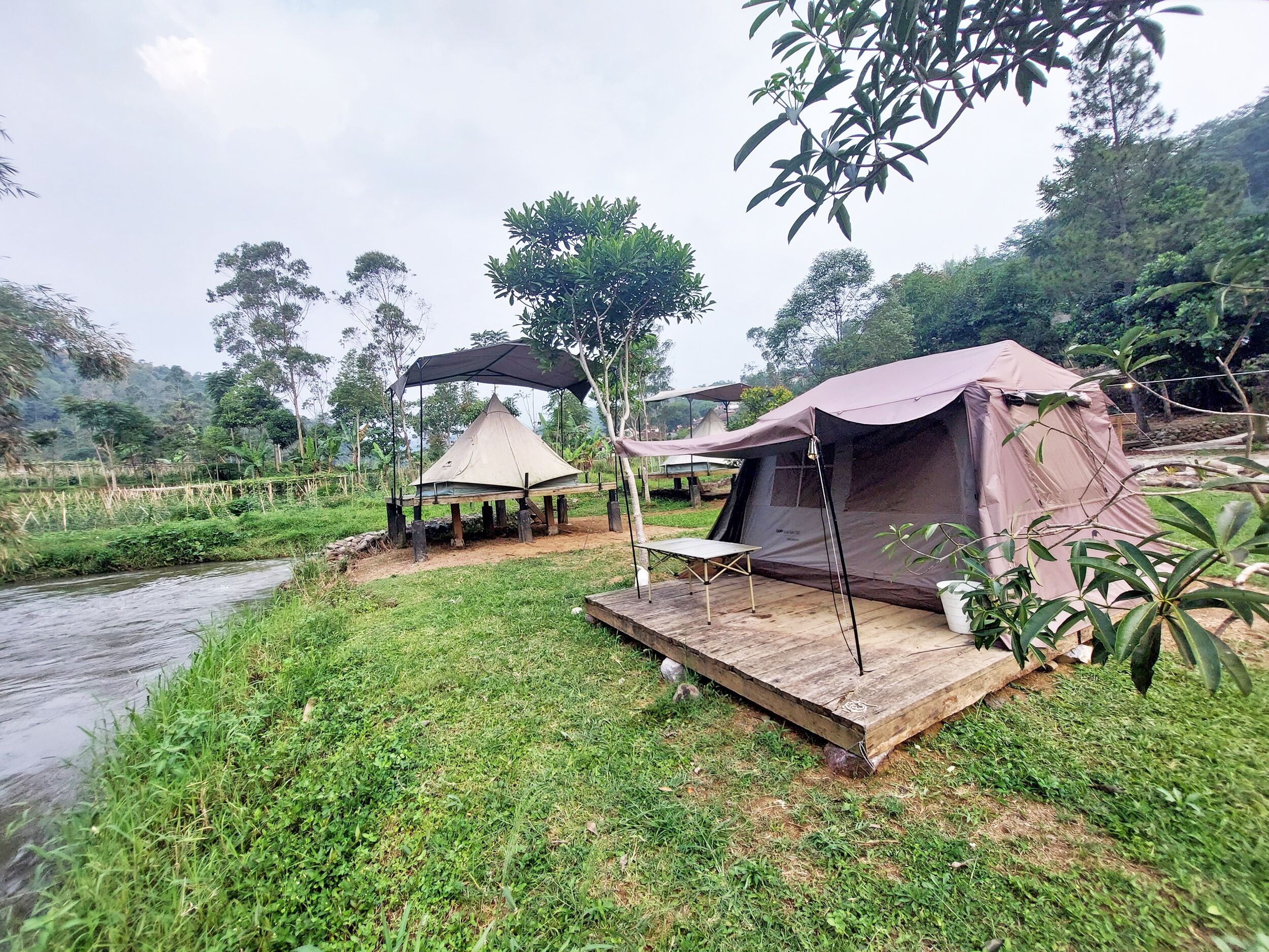 A campsite with a tent, a small table, and a shaded area.