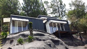 Um edifício com duas divisões, cada uma com janela e porta. Uma escadaria leva a uma varanda.