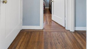 A hallway with wooden flooring, white doors, and light blue walls.