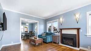 A living room with hardwood flooring, a blue sofa, a fireplace, and a dining area with a table and chairs.