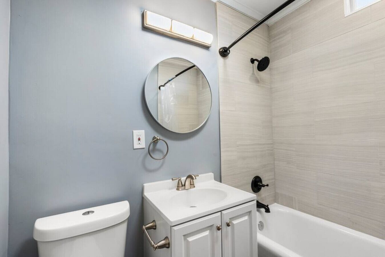 Un baño con inodoro, lavabo, espejo y bañera.