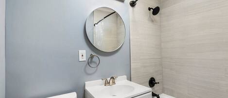 Un baño con inodoro, lavabo, espejo y bañera.