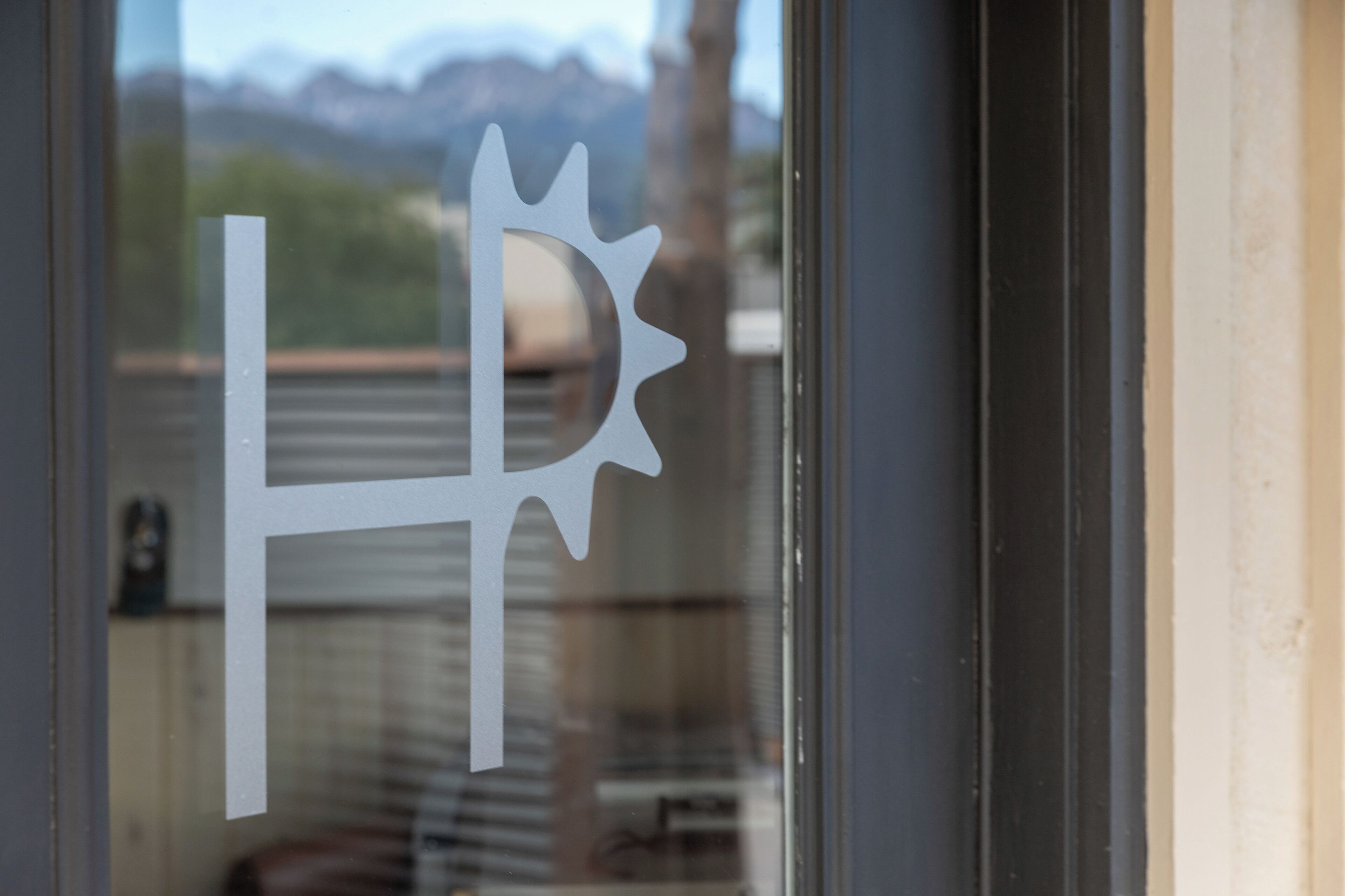 A window with a decorative metal sign featuring a sun-like design.
