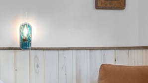 A room with a wooden bench, a brown leather chair, a wooden stump, and a wall-mounted light fixture. - Hotel Palomino (Ridgway)