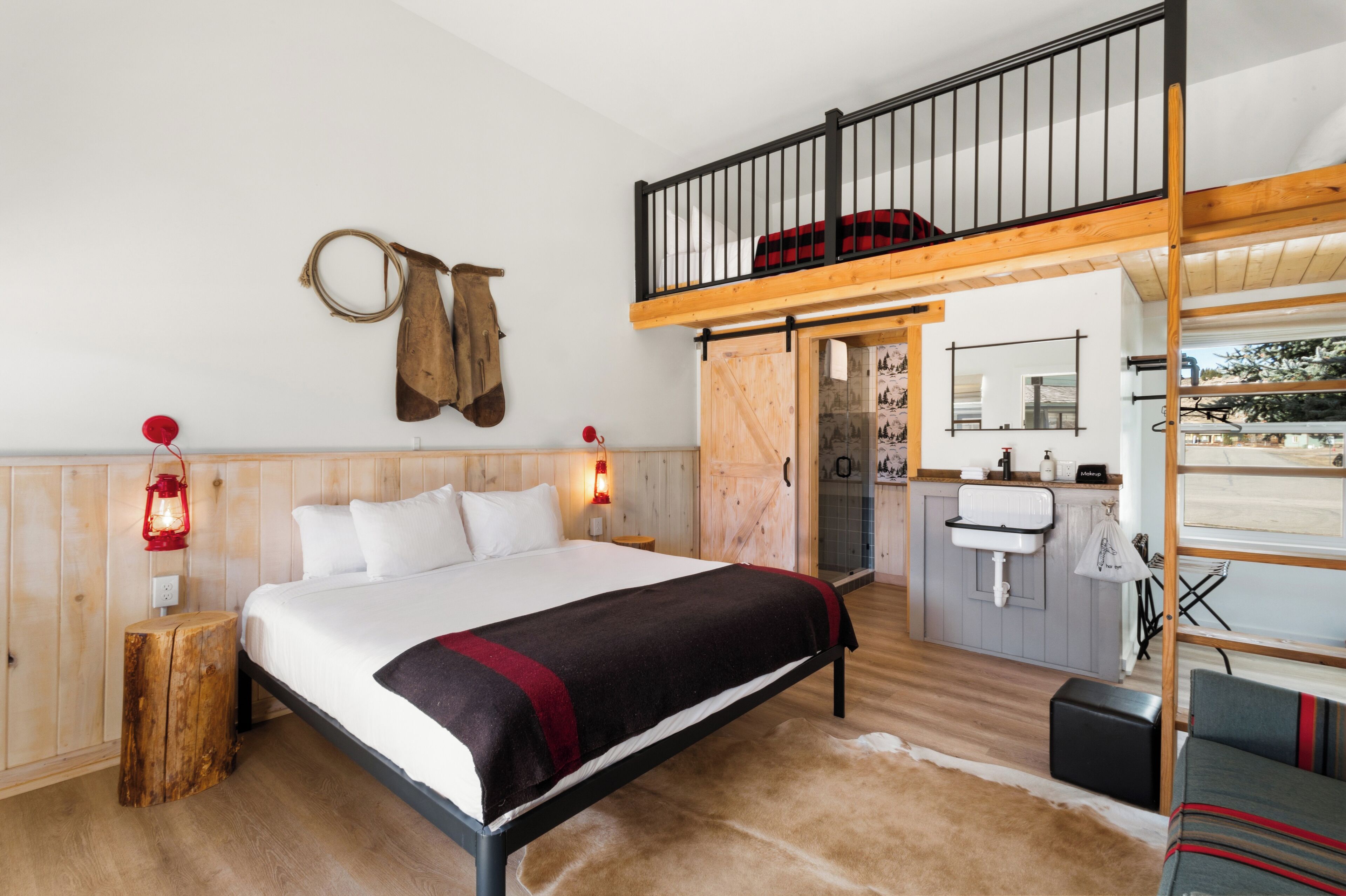 Een slaapkamer met een houten bed, een vide met een leuning, een nachtkastje van hout, een rode lantaarn en een badkamer met een wastafel en spiegel.