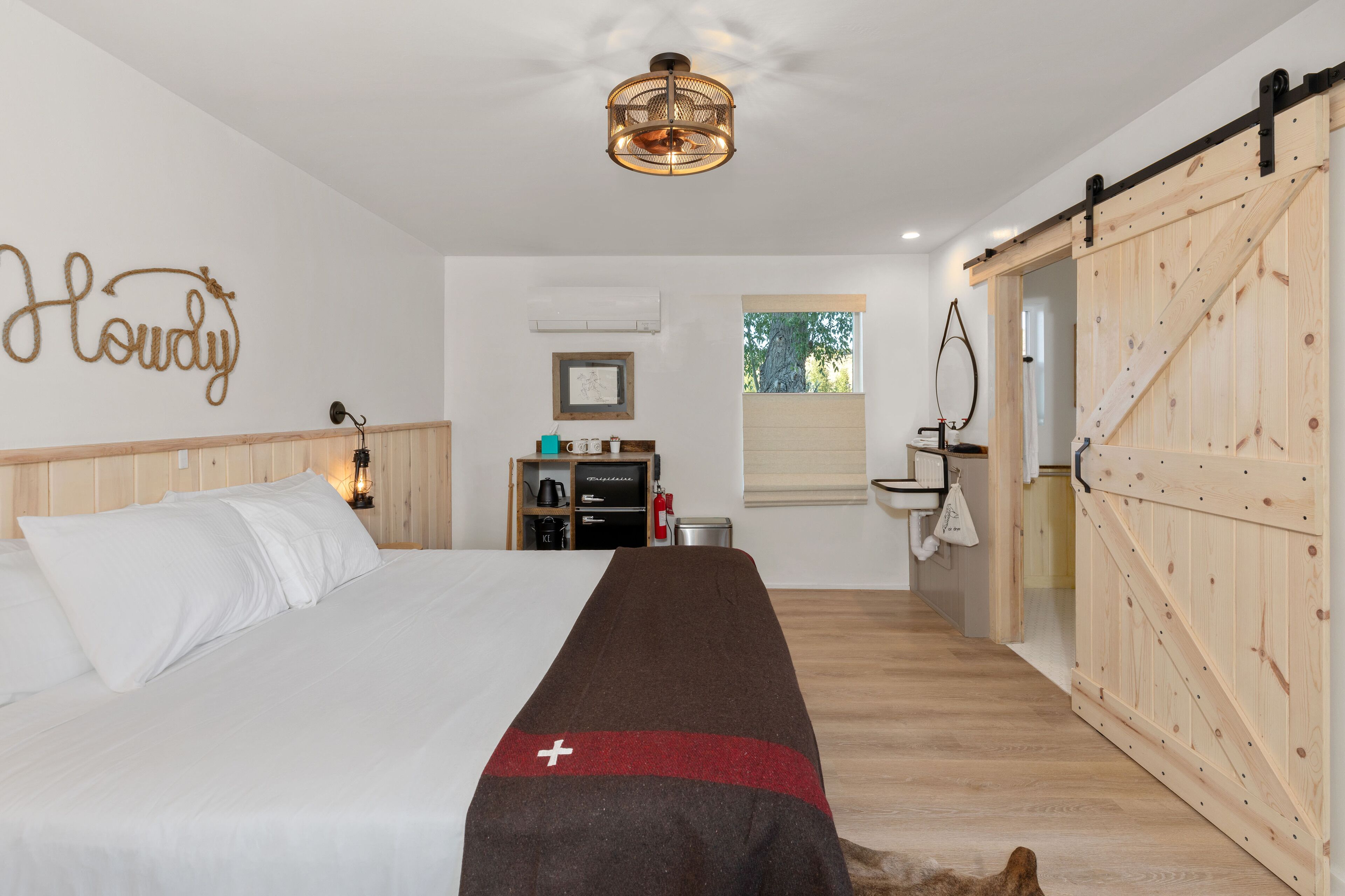 Un dormitorio con cama, armario de madera, escritorio y ventana.
