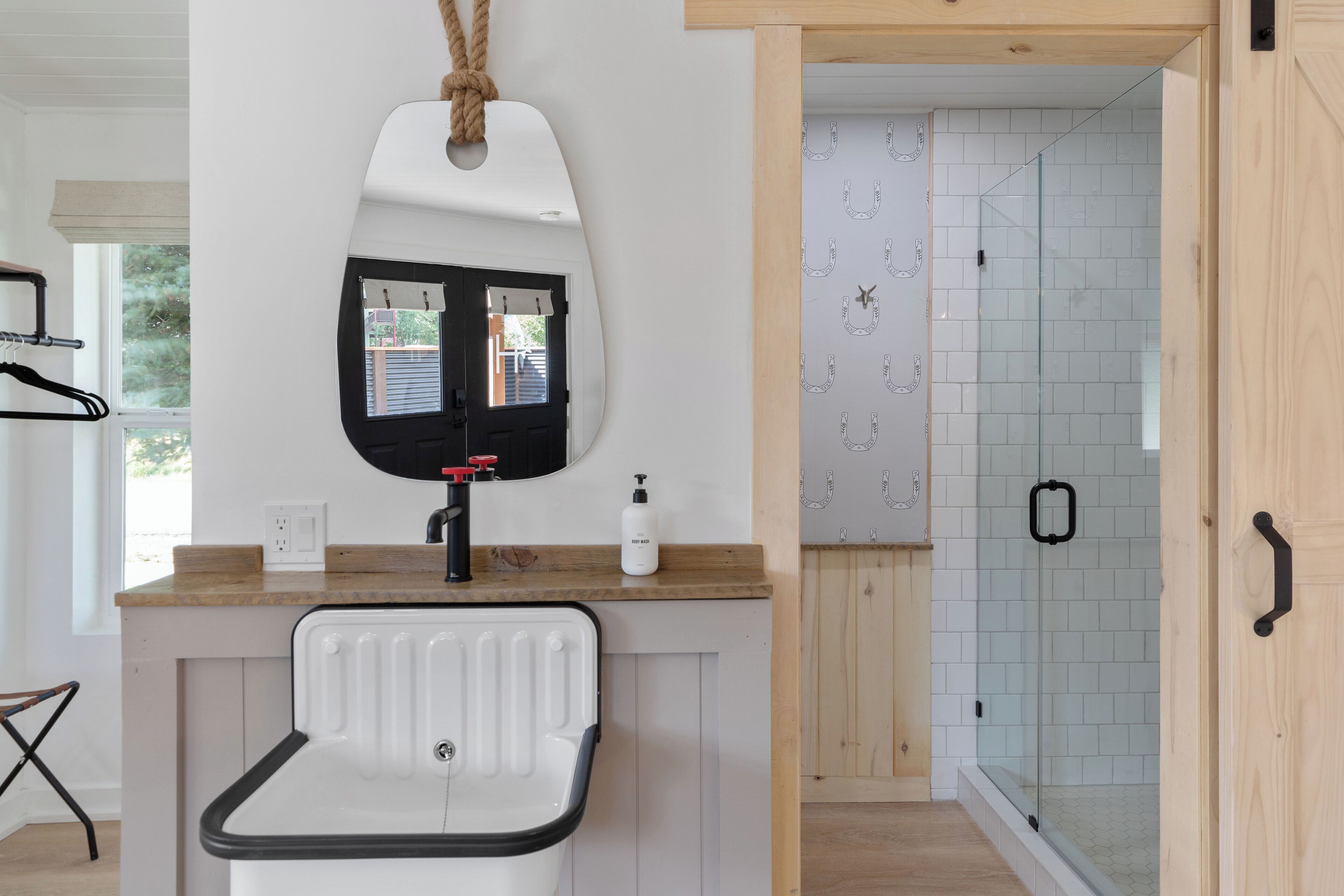 Une salle de bain avec un lavabo blanc, un miroir et une douche dotée de parois en verre.