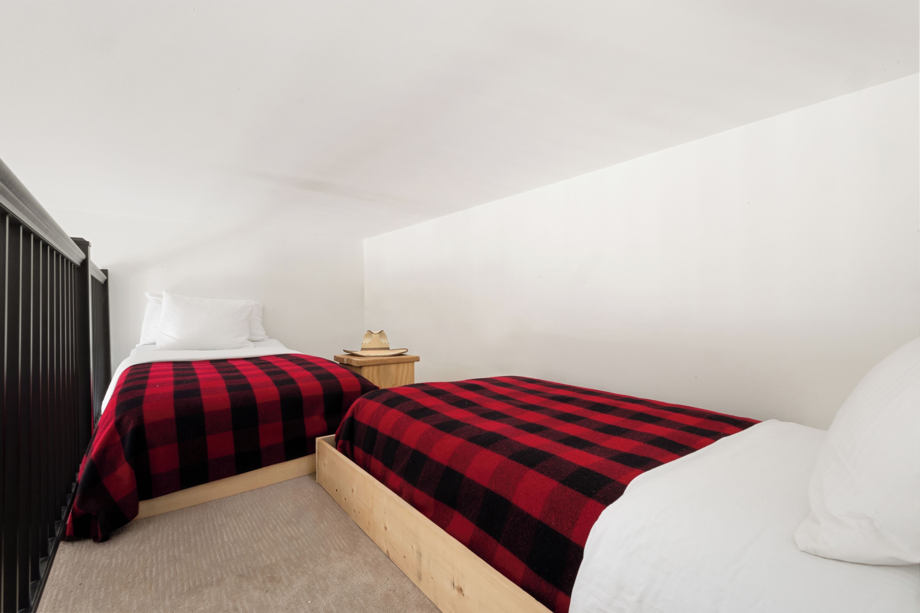 Un dormitorio con dos camas, una mesita de noche y un cabecero de madera.
