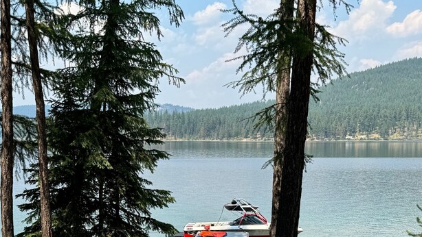 A picnic table and benches by a lake with a boat docked nearby. - Small waterfront cabin with private dock on beautiful McGregor Lake (Marion)