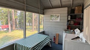 A cabin with a bed, a small kitchenette, a ceiling fan, and a window overlooking a forest. - Small waterfront cabin with private dock on beautiful McGregor Lake (Marion)