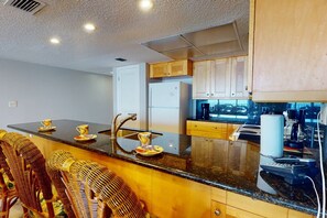 A modern kitchen with a central island, stainless steel appliances, and wooden cabinetry.