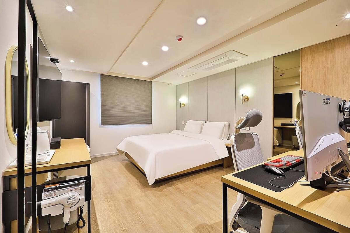Ein modernes Hotelzimmer mit Bett, Schreibtisch, Stuhl und einem großen Spiegel.