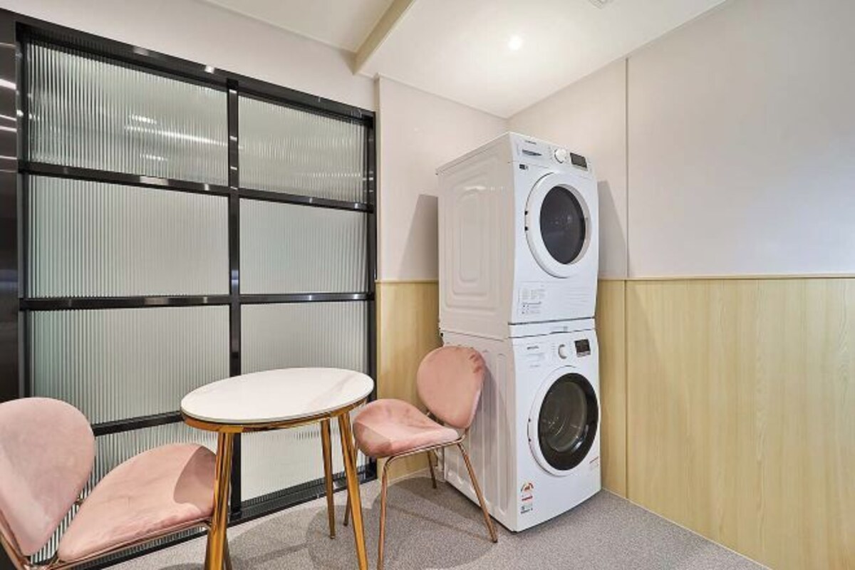 A compact room with a washing machine, a small table, and two chairs.