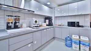 Eine moderne Küche mit grauen Schränken, einer Mikrowelle, einer Kaffeemaschine und zwei großen Wasserspendern.