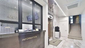 Ein Empfangstresen mit der Beschriftung "INFORMATION", modernes Design, eine Treppe und ein Marmorboden.