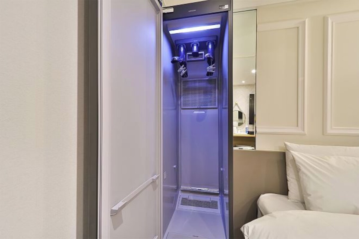 Un couloir étroit avec un sauna intégré, une porte blanche et un lit recouvert de linge de lit blanc.