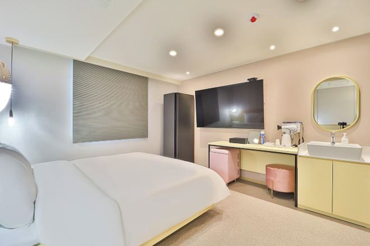 Een moderne hotelkamer met een groot bed, een kaptafel met spiegel en een televisie.