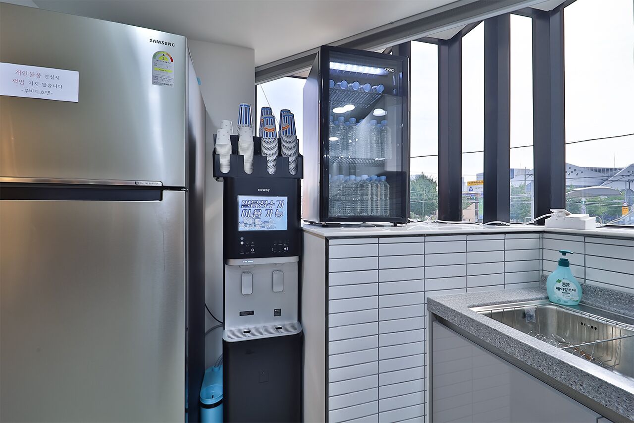 Una cocina con refrigerador de acero inoxidable, dispensador de agua y ventana con vista a la ciudad.