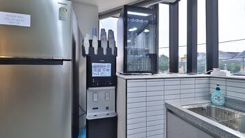 Una cocina con refrigerador de acero inoxidable, dispensador de agua y ventana con vista a la ciudad.