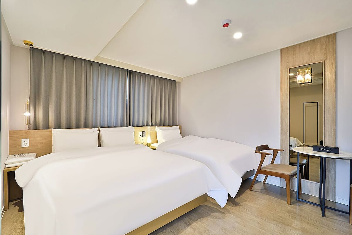 Ein Hotelzimmer mit zwei Betten, einem Schreibtisch und einem Stuhl.