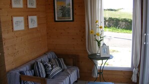 Una habitación acogedora con una pared de madera, un sofá a rayas, una mesita con un florero y un cuadro enmarcado.
