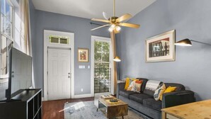 A living room with a gray sofa, a wooden coffee table, a ceiling fan, and a framed picture on the wall.