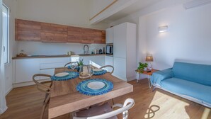 Eine moderne Küche mit Holzschränken, einem Esstisch mit blauen Platzsets und einem blauen Sofa.