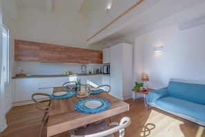 Eine moderne Küche mit Holzschränken, einem Esstisch mit blauen Platzsets und einem blauen Sofa.