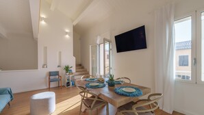 Ein moderner Essbereich mit einem Holztisch, Stühlen und einem an der Wand befestigten Fernseher.