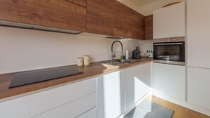 Eine moderne Küche mit Holzausbau, einem Edelstahlbackofen und einer Arbeitsplatte mit einem Wasserkocher.