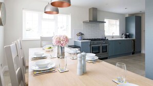 A modern kitchen with a dining area, featuring a central island, pendant lighting, and a view of the city.