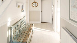 Ein geräumiger Korridor mit einer Holzbank, einer weißen Treppe und einer hängenden Leuchte.