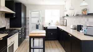 Une cuisine moderne avec des meubles de couleur noire, un plan de travail en bois et un îlot central.