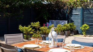 A wooden dining table set for four with chairs, a white lantern, and potted plants. - Wonderful Seafront Home - Panoramic Ocean Views (Selsey)