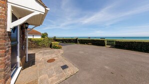 A residential property with a paved driveway, a brick house, and a view of the sea. - Wonderful Seafront Home - Panoramic Ocean Views (Selsey)