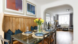 A dining area with a glass table, blue plates, and a vase of yellow flowers. - Wonderful Seafront Home - Panoramic Ocean Views (Selsey)