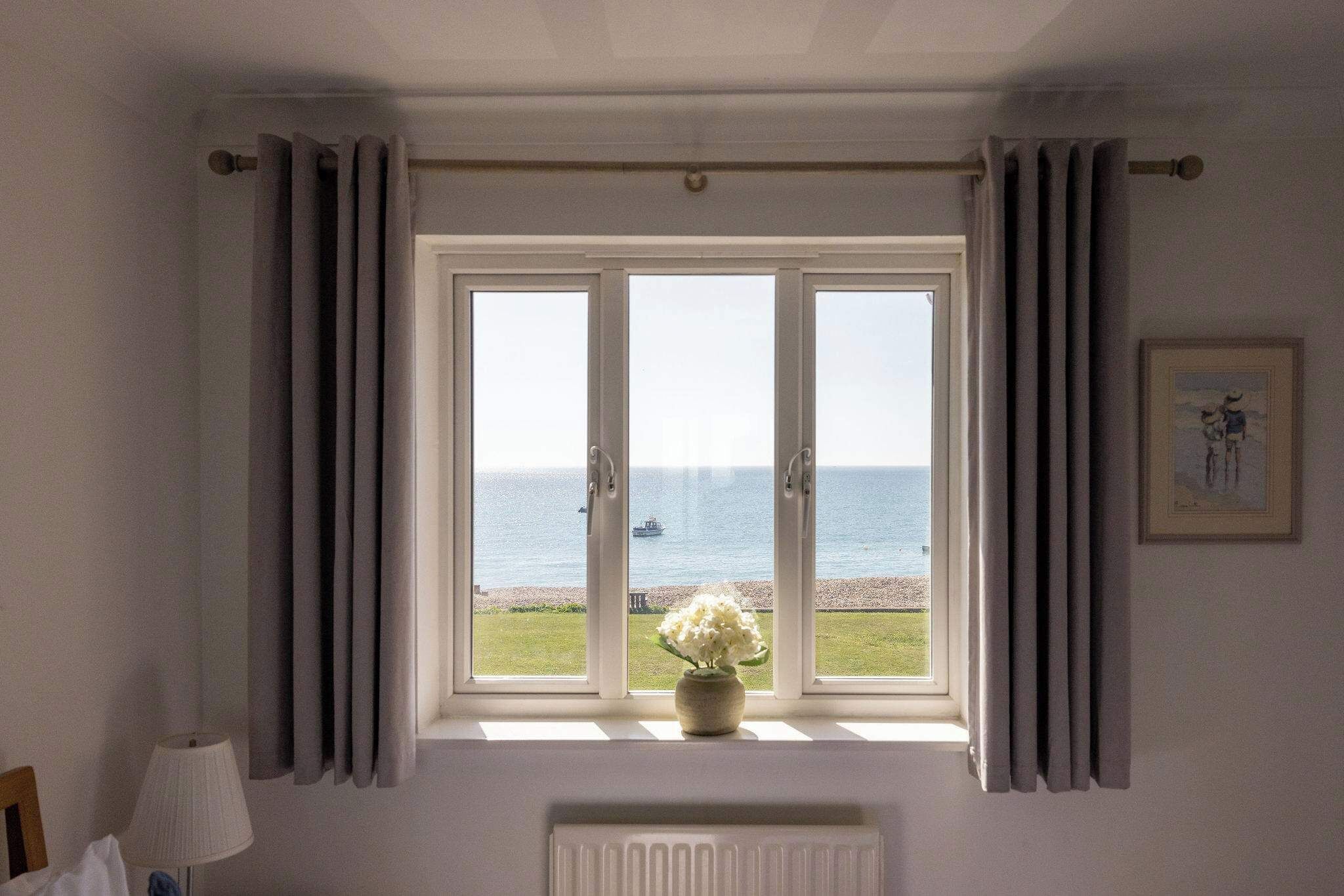 Ein Zimmer mit großem Fenster und Blick auf ein Gewässer, darunter eine Heizung und links eine Lampe.