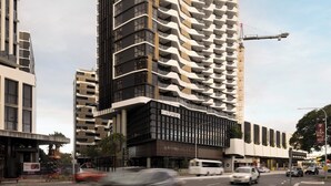 Un edificio moderno de gran altura con varios balcones, una grúa de construcción y una calle concurrida llena de vehículos.
