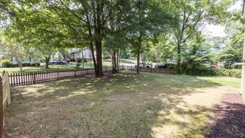 A residential backyard with a wooden fence, trees, and a grassy lawn.