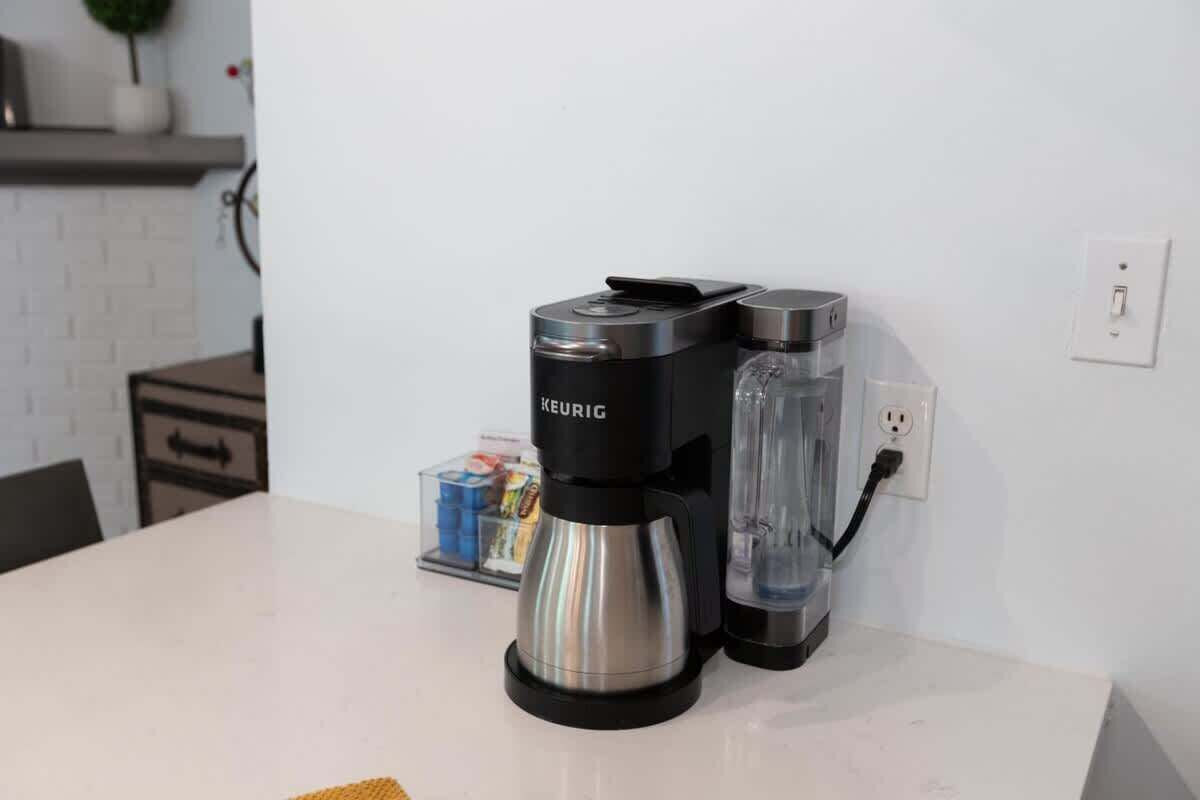A kitchen with a coffee maker, a water dispenser, and a coffee pot on the counter.