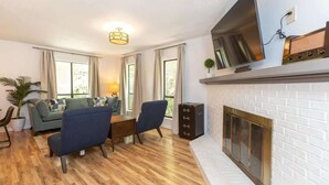 A living room with a fireplace, a TV mounted above it, and a sofa set. - Cozy Single-Story near Pineville Hospital, games (Charlotte)