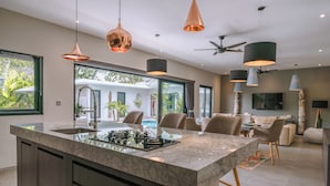 Una cocina moderna con una isla central, iluminación colgante y vistas al exterior.