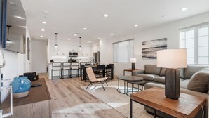 Una sala moderna con sofá, mesa de centro, televisor y zona de comedor con sillas y mesa.