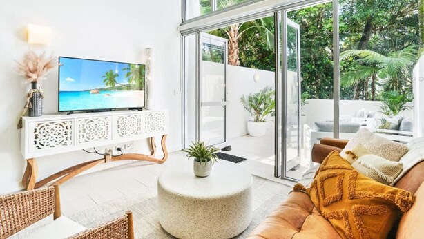 A modern living room with a TV, a round coffee table, and a sofa with a throw pillow.
