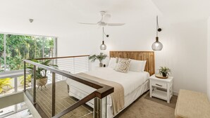 A modern bedroom with a bed, bedside tables, a ceiling fan, and a balcony with a railing.