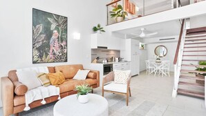 A modern living room with a brown sofa, a round coffee table, and a painting of birds on the wall.