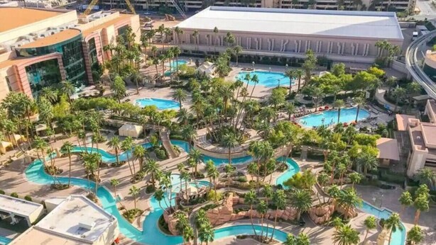 An aerial view of a resort with multiple interconnected swimming pools, palm trees, and a large building in the background. - *No Resort Fee*MGM StripView*Jacuzzi*F1 Trackview* (Las Vegas)