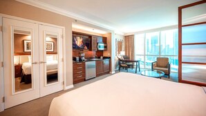 A hotel room with a large bed, a kitchenette, a dining area, and a view of the city. - *No Resort Fee*MGM StripView*Jacuzzi*F1 Trackview* (Las Vegas)