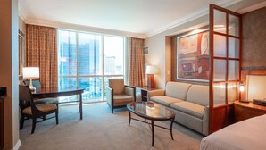 A hotel room with a large window, a sofa, a coffee table, a desk with a chair, and a bed. - *No Resort Fee*MGM StripView*Jacuzzi*F1 Trackview* (Las Vegas)